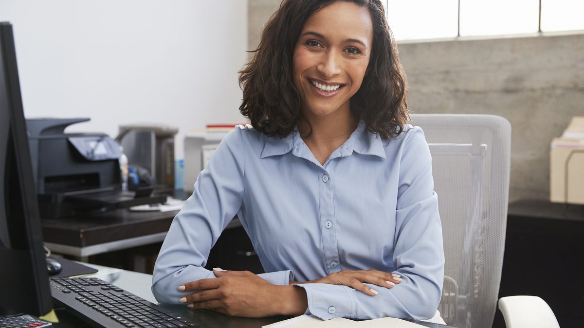 Young female professional at desk smiling to camera