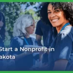 A smiling woman with curly hair wearing a blue lanyard is surrounded by diverse volunteers outdoors. Text overlay reads, “How to start a nonprofit in South Dakota.”