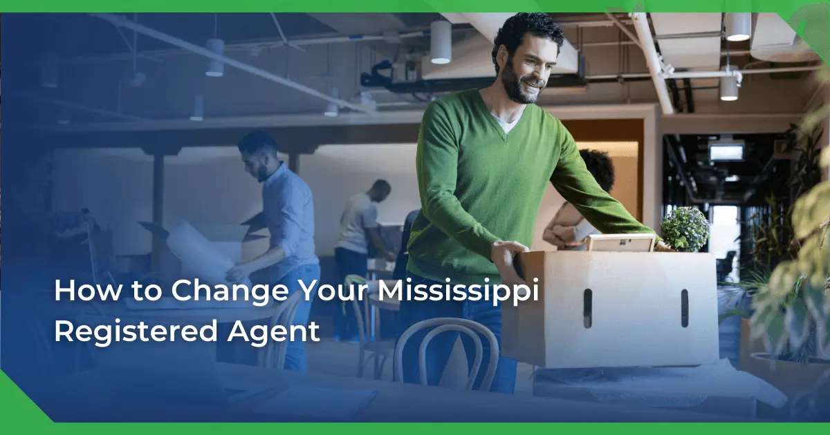 Man in a green sweater smiling and carrying a box in an office setting. Others are packing or working. Text reads Mississippi change of registered agent for a nonprofit.