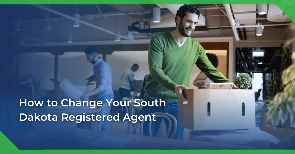 Man in a green sweater smiling and carrying a box in an office setting. Others are packing or working. Text reads South Dakota change of registered agent for a nonprofit.